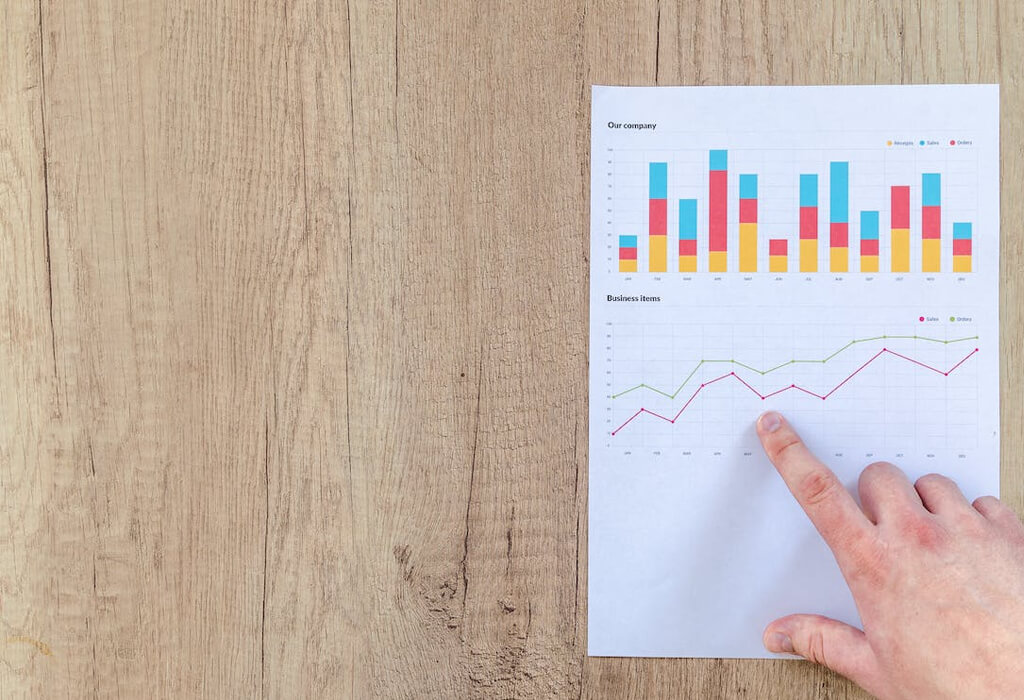 Image of someone pointing at a line graph underneath a colourful bar chart