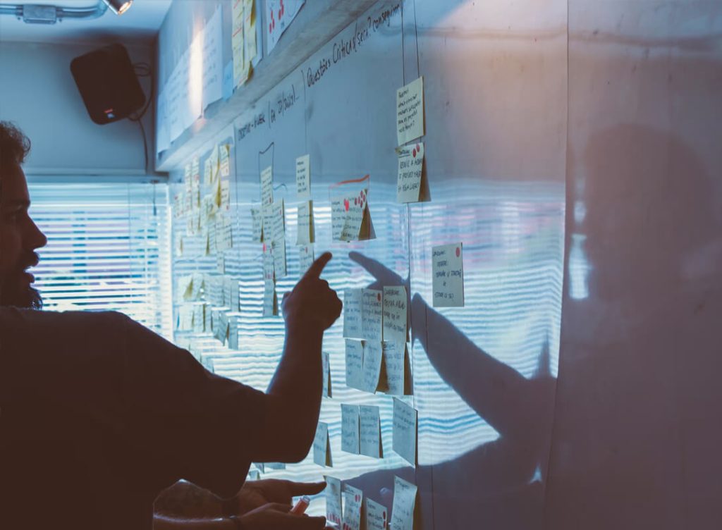 Somebody pointing at post-it notes on a whiteboard